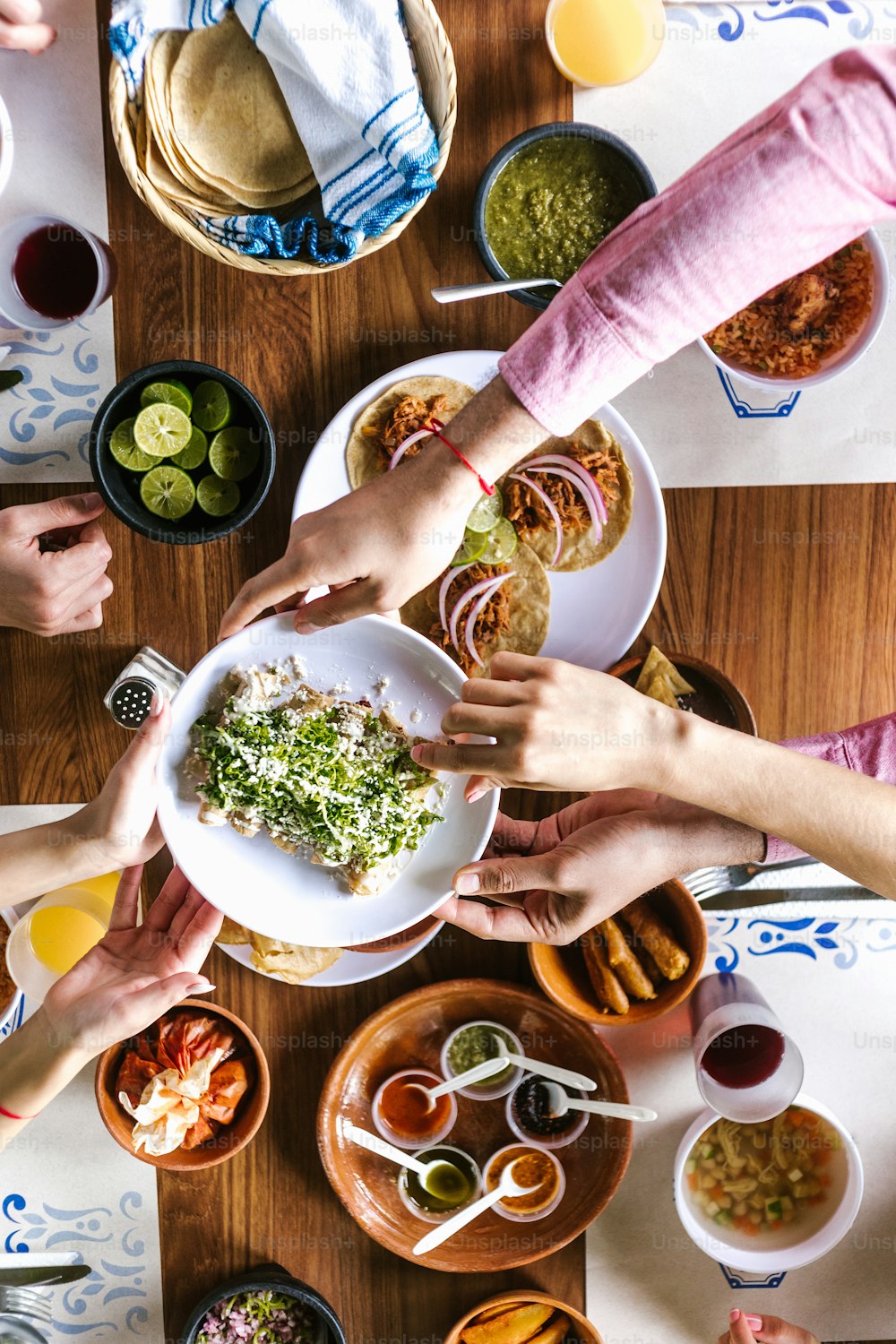 メキシコのタコスや伝統的な食べ物、スナック、テーブル、上面図の人々の手を食べるラテン系の友達のグループ。メキシコ料理ラテンアメリカ