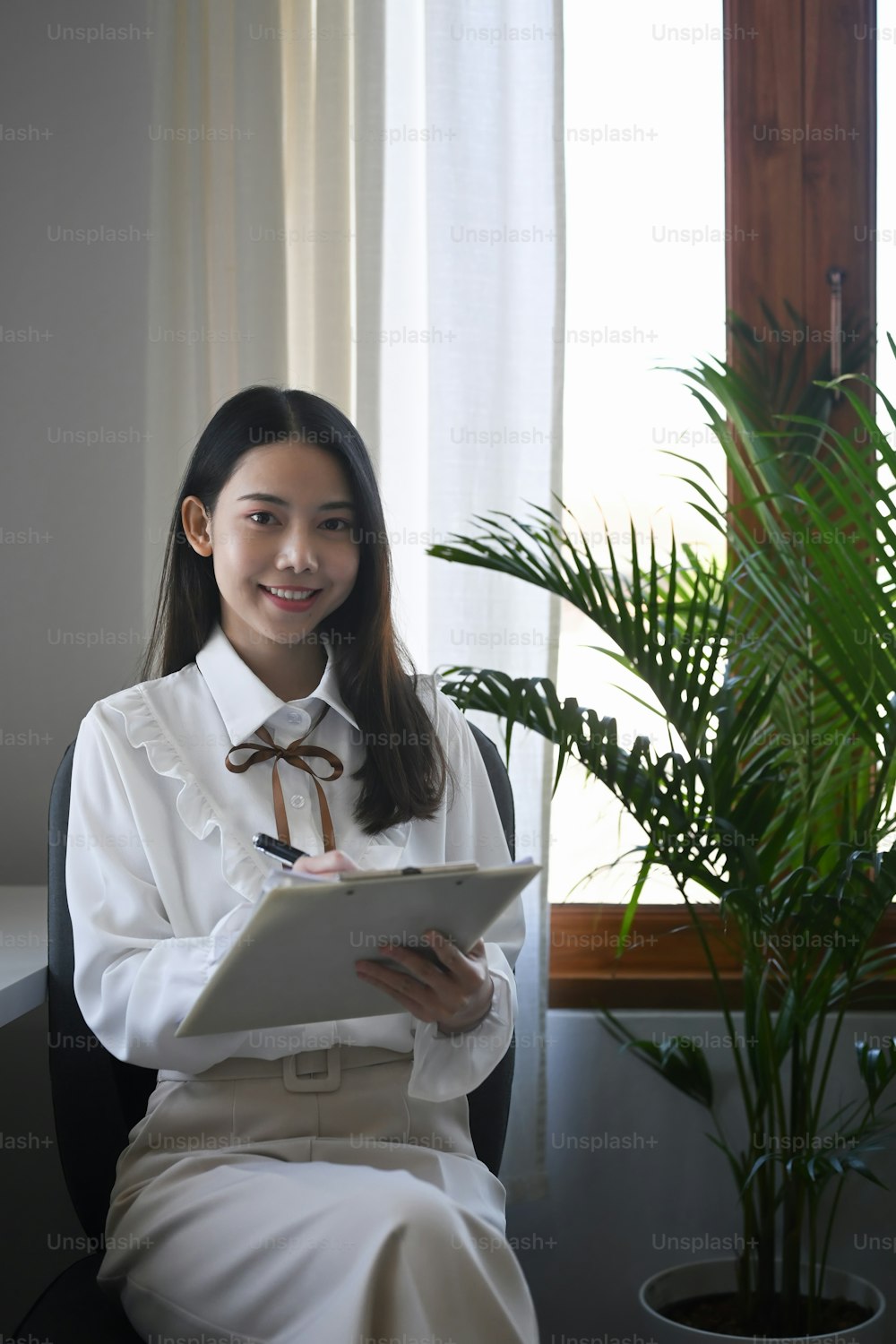 Pretty asian businesswoman sitting in comfortable office and checking report.