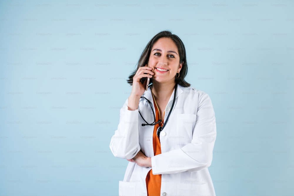 mujer médica latina sosteniendo el teléfono móvil sobre fondo azul riendo en México América Latina