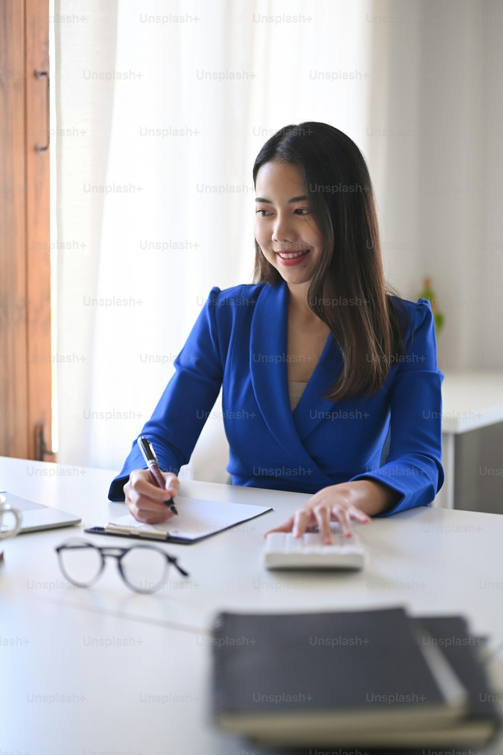 Portrait of cheerful asian business woman working in bright office.