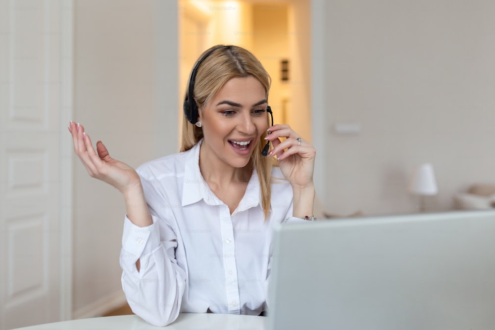Femme blonde heureuse portant des écouteurs et un microphone regardant la webcam, souriant à la caméra, riant pendant une réunion virtuelle ou un appel vidéo. Employé travaillant à domicile. Vue d’écran de la tête
