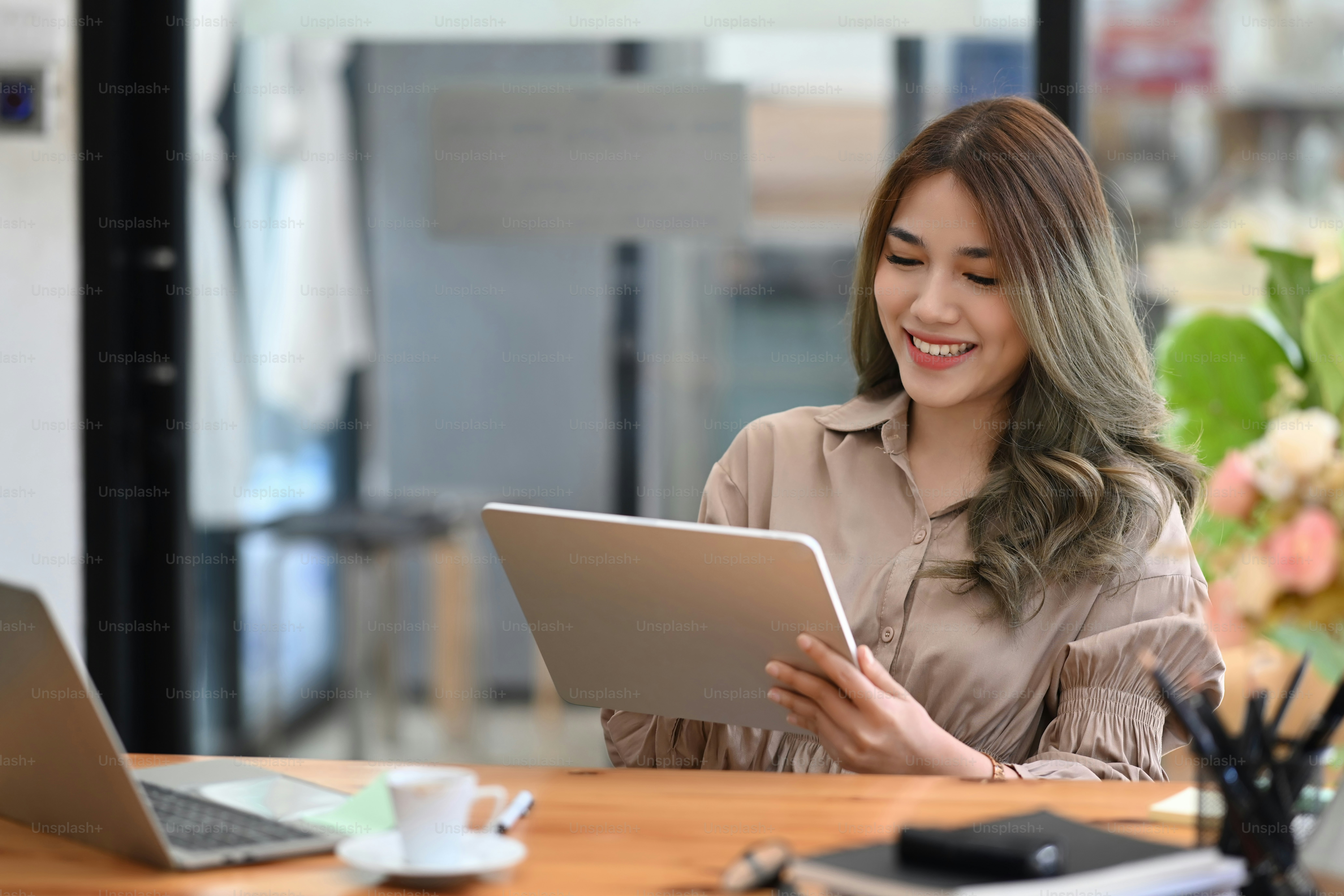 Designer créative souriante utilisant une tablette numérique sur son lieu de travail.