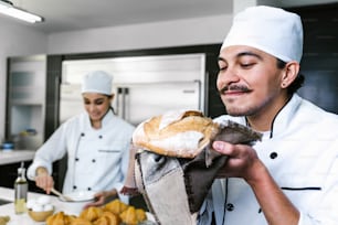 young Latin man baker and baking bread on oven at kitchen in Mexico Latin America