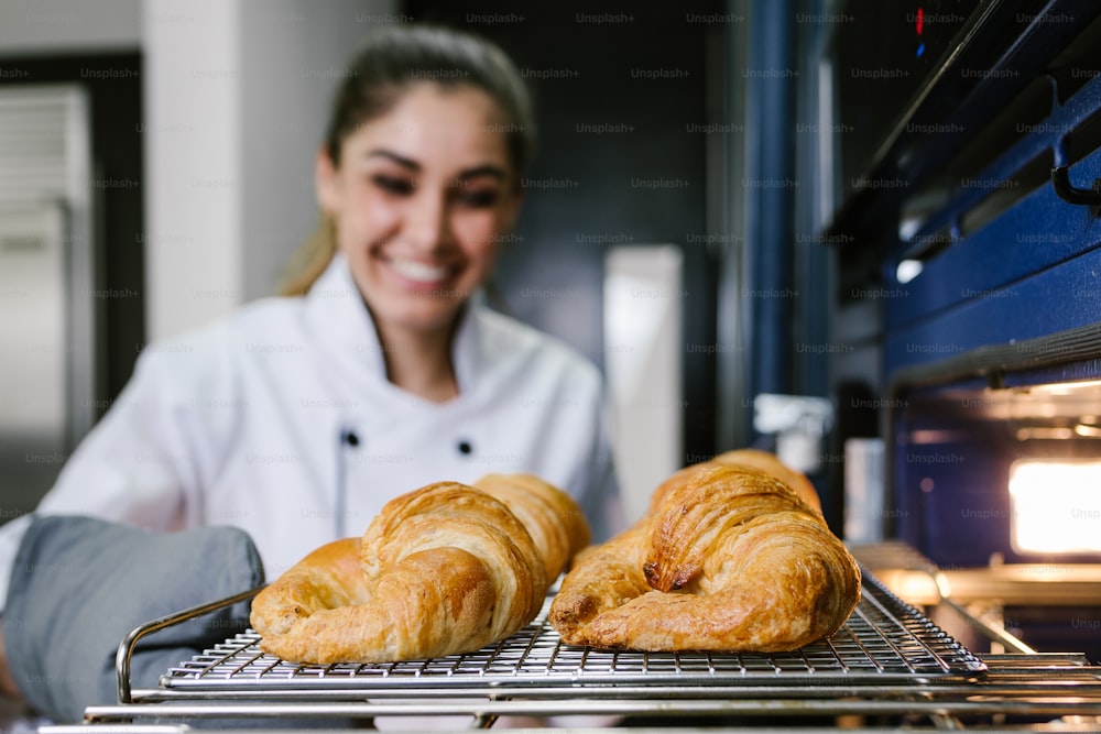young Latin woman baking croissant bread on oven at kitchen in Mexico Latin America