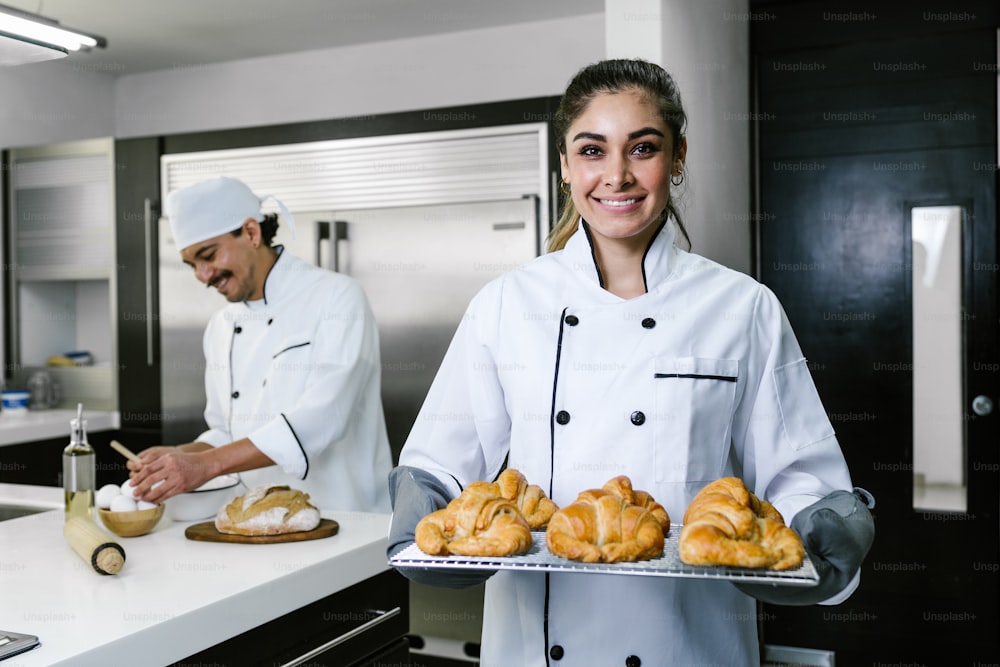 giovane donna latina che cuoce il pane del croissant sul forno in cucina in Messico America Latina