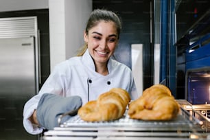 giovane donna latina che cuoce il pane del croissant sul forno in cucina in Messico America Latina