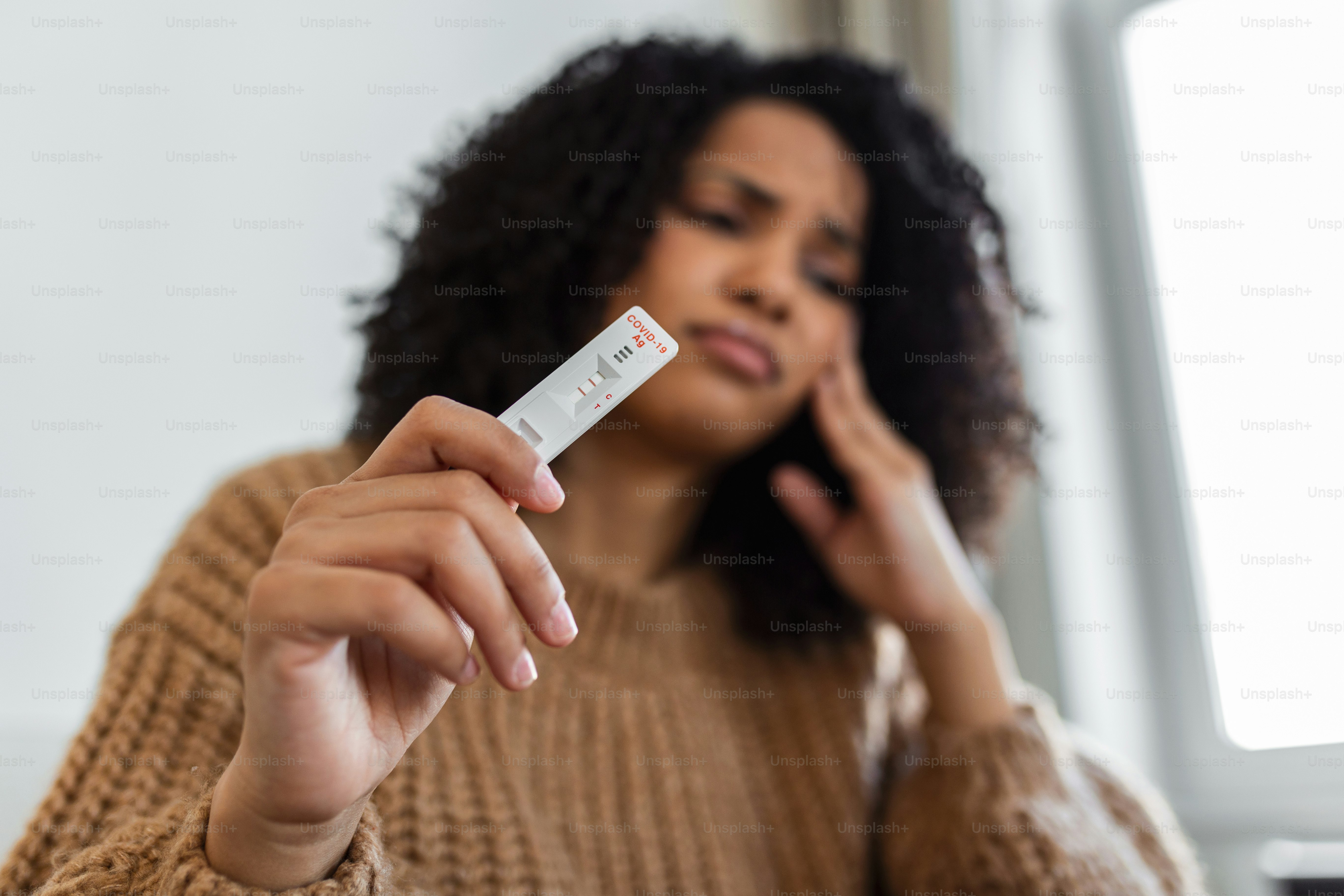 Close-up shot of womans hand holding a positive Antigen test device. Showing result after a positive test. hand holding positive Coronavirus/Covid-19 rapid test. Focus is on the test.