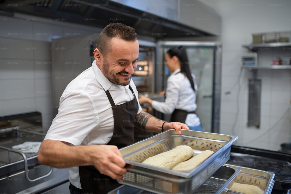 A chef and cook working on their dishes indoors in restaurant kitchen.