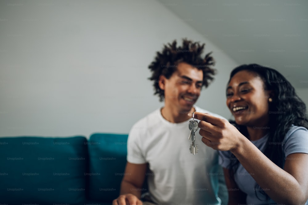 買った新しいアパートの鍵を見せて大喜びのアフリカ系アメリカ人の夫婦。新しいアパートと住宅ローンのコンセプト。キーに焦点を合わせます。
