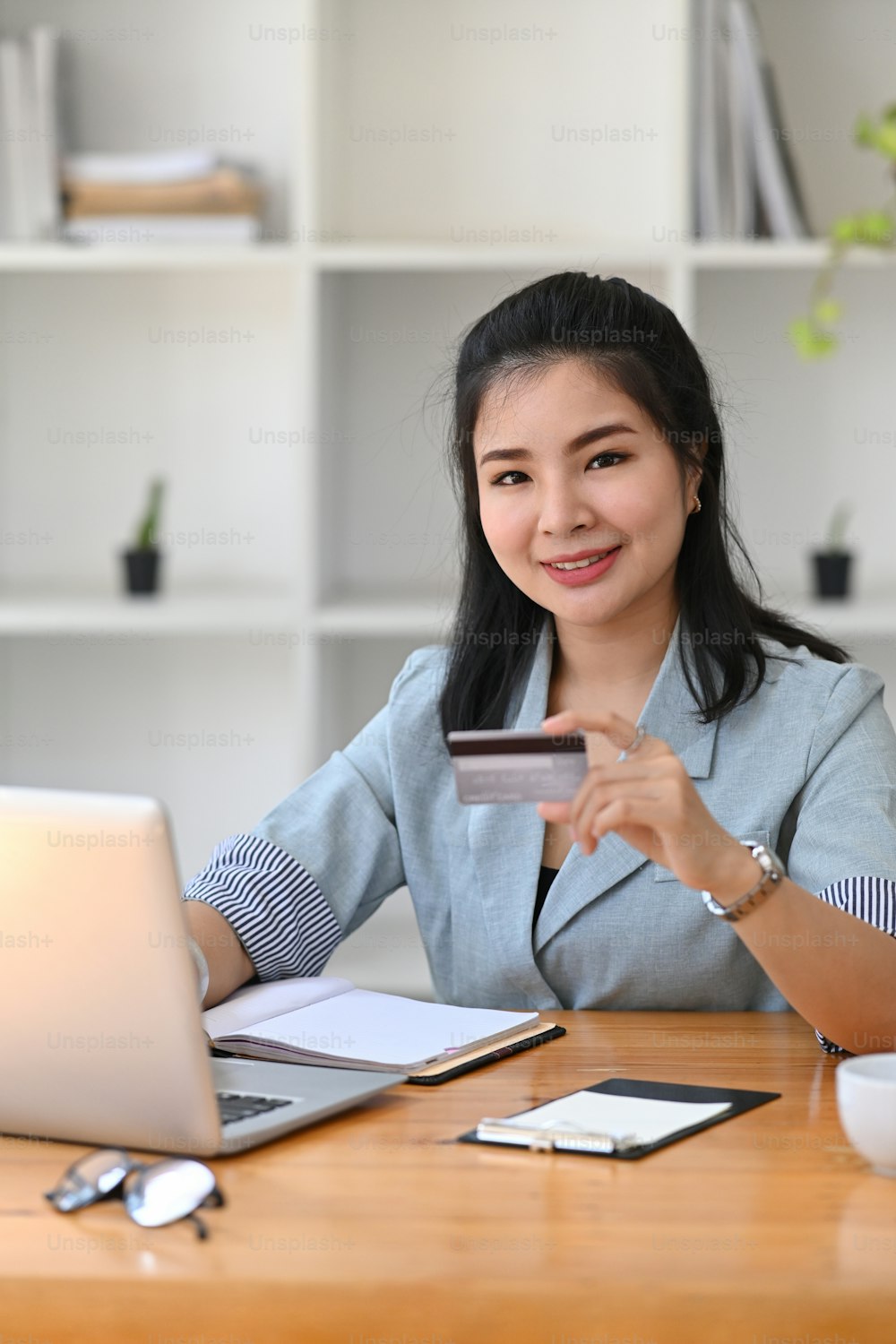 肖像画の若いアジアの女性は、クレジットカードをホールし、オンラインでの支払いのためにコンピュータのラップトップを使用しています。
