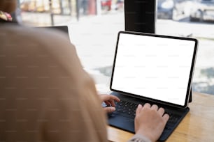 Over shoulder view of female freelancer hands typing on wireless keyboard of digital tablet.