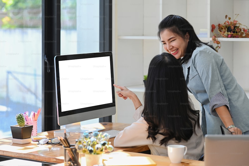 Two cheerful female business colleagues working together at modern office.