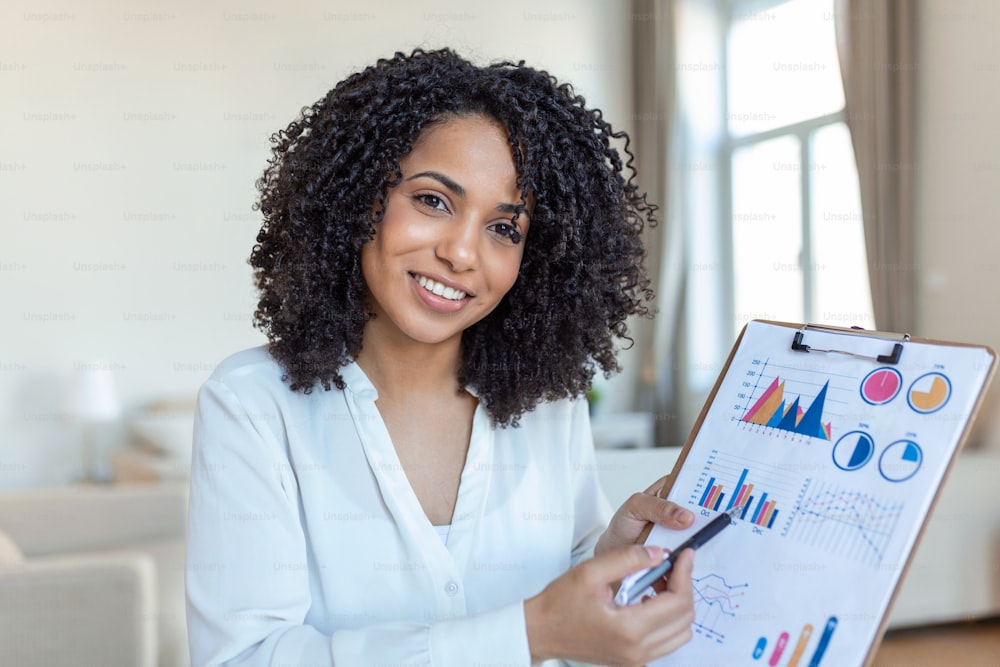 Focused business woman presenting charts and graphs on video call online. Young business woman having conference call with client on laptop. Young woman explaining how business work