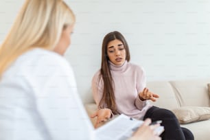 Woman at therapy session. Attentive psychologist. Attentive psychologist holding pencil in her hands making written notes while listening to her client