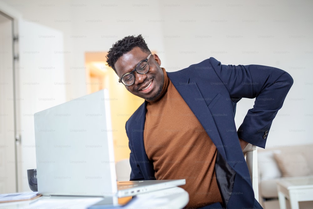 Shot of a young businessman suffering from a backache while working at his desk in his office.