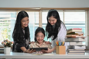 Group of students using digital tablet and doing online homework together at home.