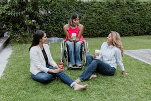 latin business woman transgender on wheels chair and friends sitting on grass and meditating at terrace office in Mexico Latin America