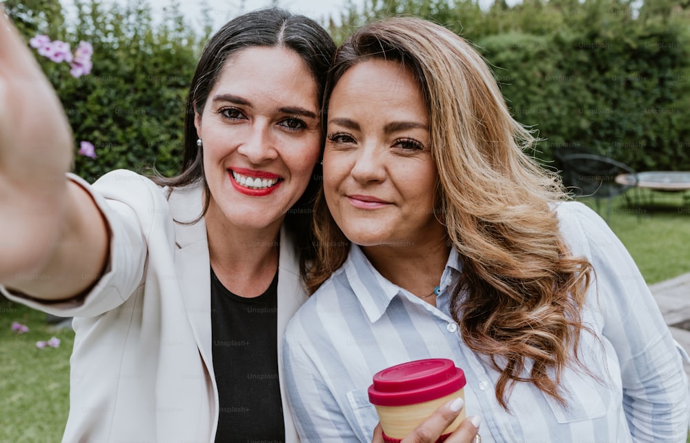 two latin business women taking a photo selfie with mobile phone at terrace office in Mexico Latin America