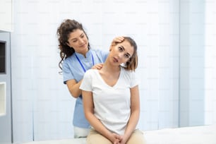女性の理学療法士またはカイロプラクターが患者の首を調整します。理学療法、リハビリテーションのコンセプト。白い背景の正面図(コピースペースあり)
