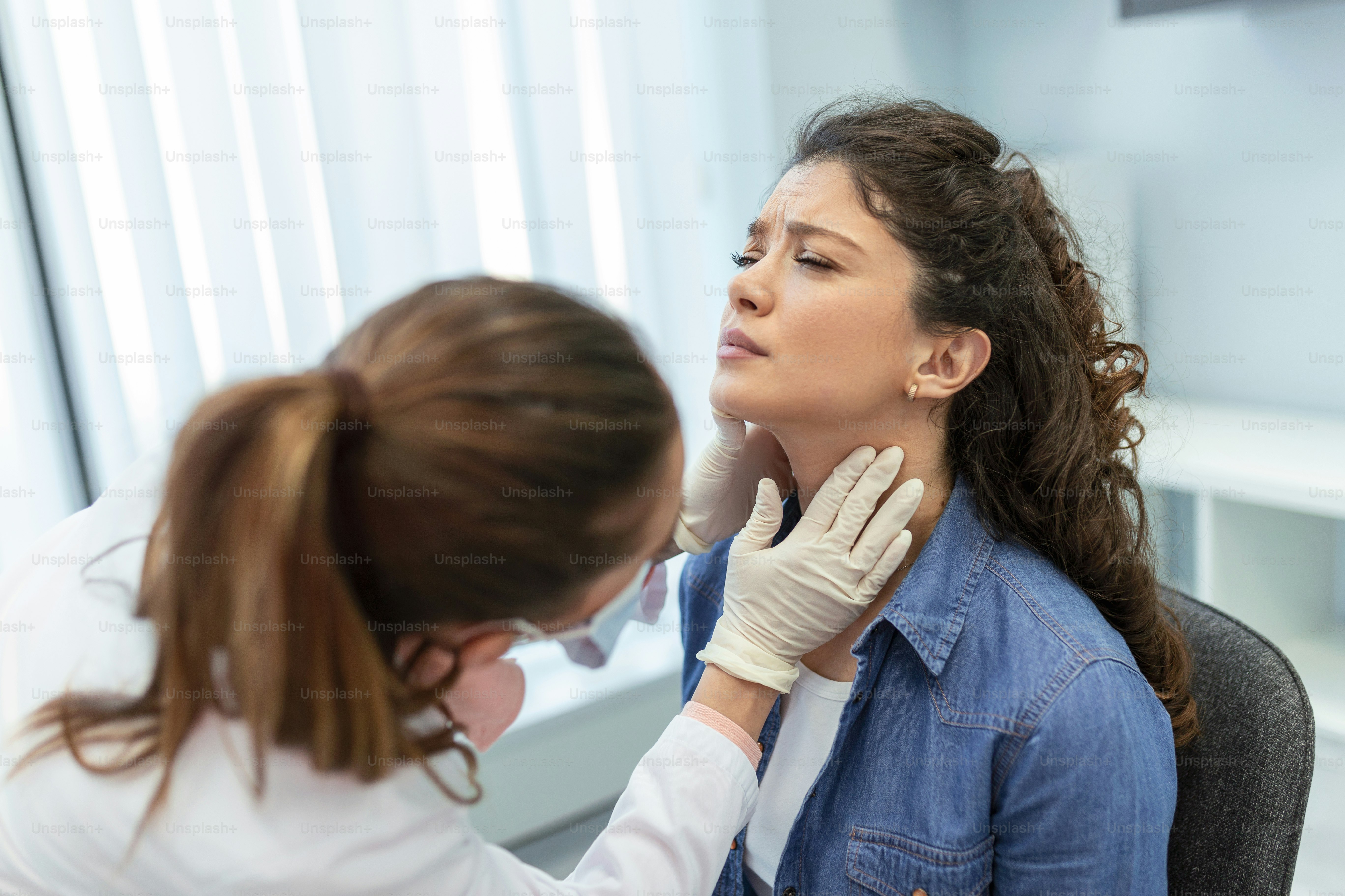 Concept of professional consultation in therapist system. Close up portrait of doctor woman examining tonsils of young lady in medical office
