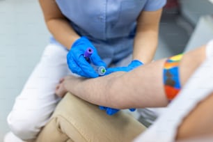 Nahaufnahme Hand der Krankenschwester, des Arztes oder des Medizintechnikers in blauen Handschuhen bei der Blutentnahme bei der Blutentnahme bei einem Patienten im Krankenhaus.