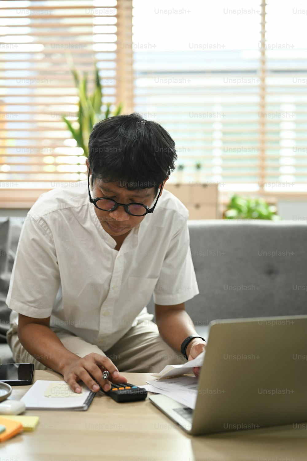 Homem focado usando laptop e calculando as despesas domésticas. Conceito de finanças domésticas.