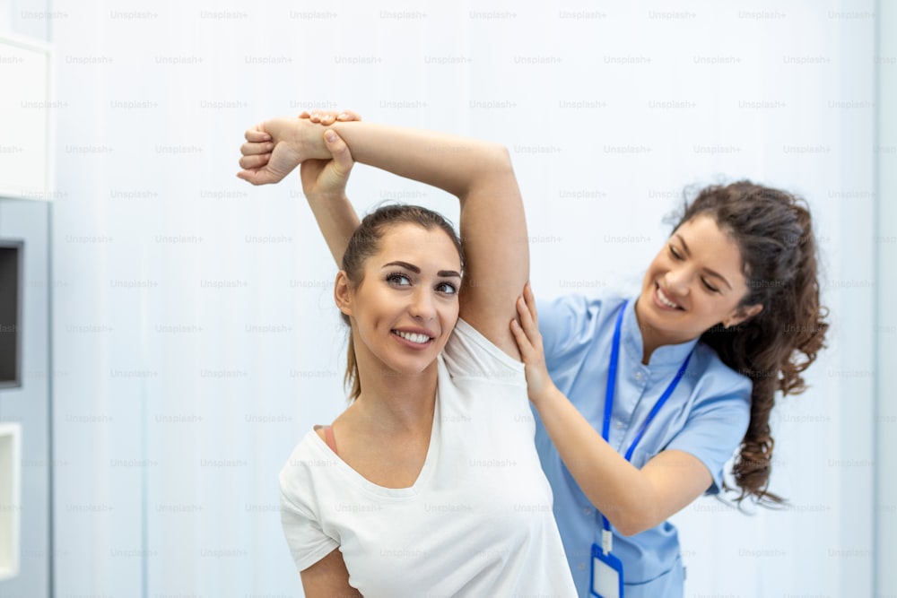 医師または理学療法士は、アスリート患者の負傷した腕の治療、ストレッチや運動、クリニックでのリハビリテーション療法の痛みの検査を行っています。