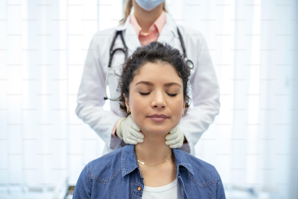 Endocrinologist examining throat of young woman in clinic. Women with thyroid gland test . Endocrinology, hormones and treatment. Inflammation of the sore throat