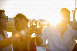 Verschwommene Gruppe von Menschen Männer und Frauen Freunde genießen Party trinken Champagner zusammen, während Katamaranboot bei Sommersonnenuntergang segelt. Männer und Frauen entspannen Outdoor-Lifestyle-Aktivität im Reiseurlaub