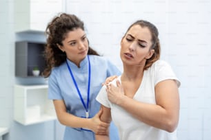 Femme médecin ostéopathe en uniforme médical réparant les articulations de l’épaule et du dos des patientes dans une clinique de thérapie manuelle lors de la visite. Ostéopathe professionnel pendant le travail avec le concept patient