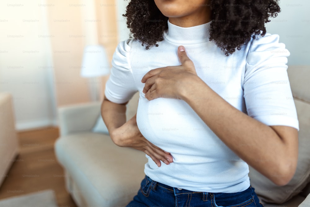 Afroamerikanische Frau, die Klumpen auf ihrer Brust auf Anzeichen von Brustkrebs überprüft. Frau leidet unter Schmerzen in der Brust. BSE oder Selbstuntersuchung der Brust. Richtlinien zur Überprüfung auf Brustkrebs.