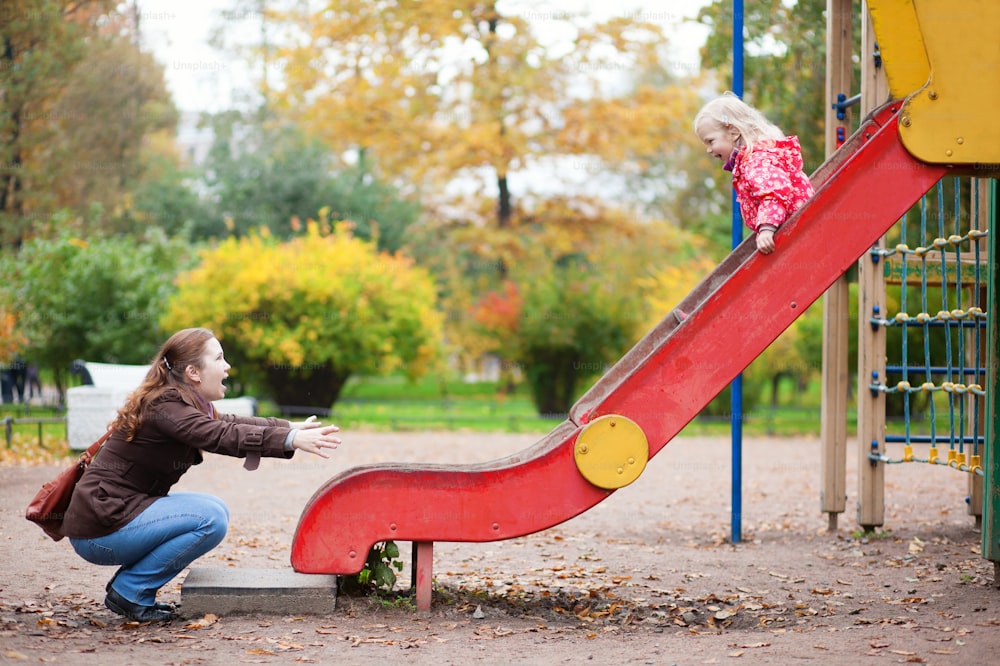 Mother and her little daughter are having fun together at the playground