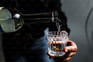 Barman hands serving mexican mezcal shot in a traditional glass with tacos and food at background in Mexico