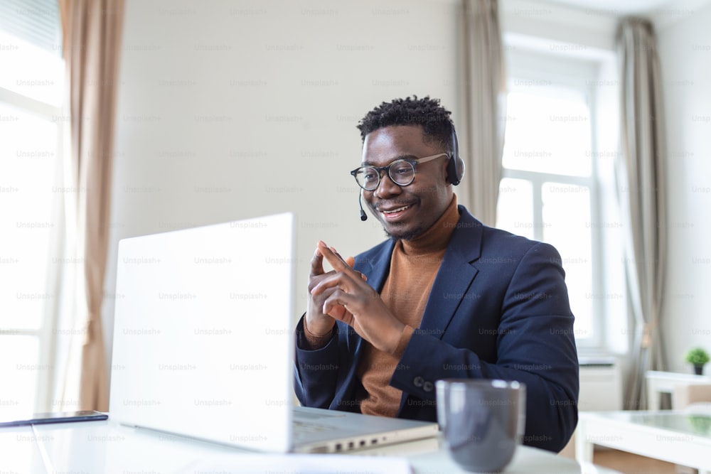 Uomo afroamericano eccitato che indossa le cuffie che legge buone notizie in e-mail, ottiene un nuovo lavoro, promozione, usando il computer portatile, guardando lo schermo e urlando di gioia, mostrando gesto di sì, celebrando