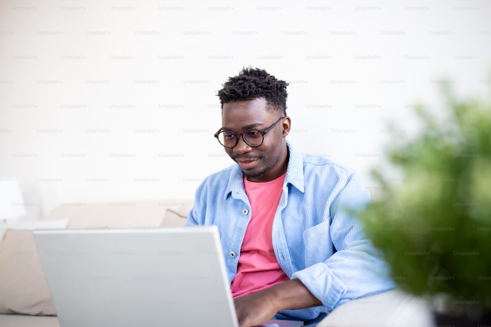 Junge und entschlossene schwarze Studentin, die nachts zu Hause lernt, mit Hilfe eines Laptops und einem Internetanruf.
