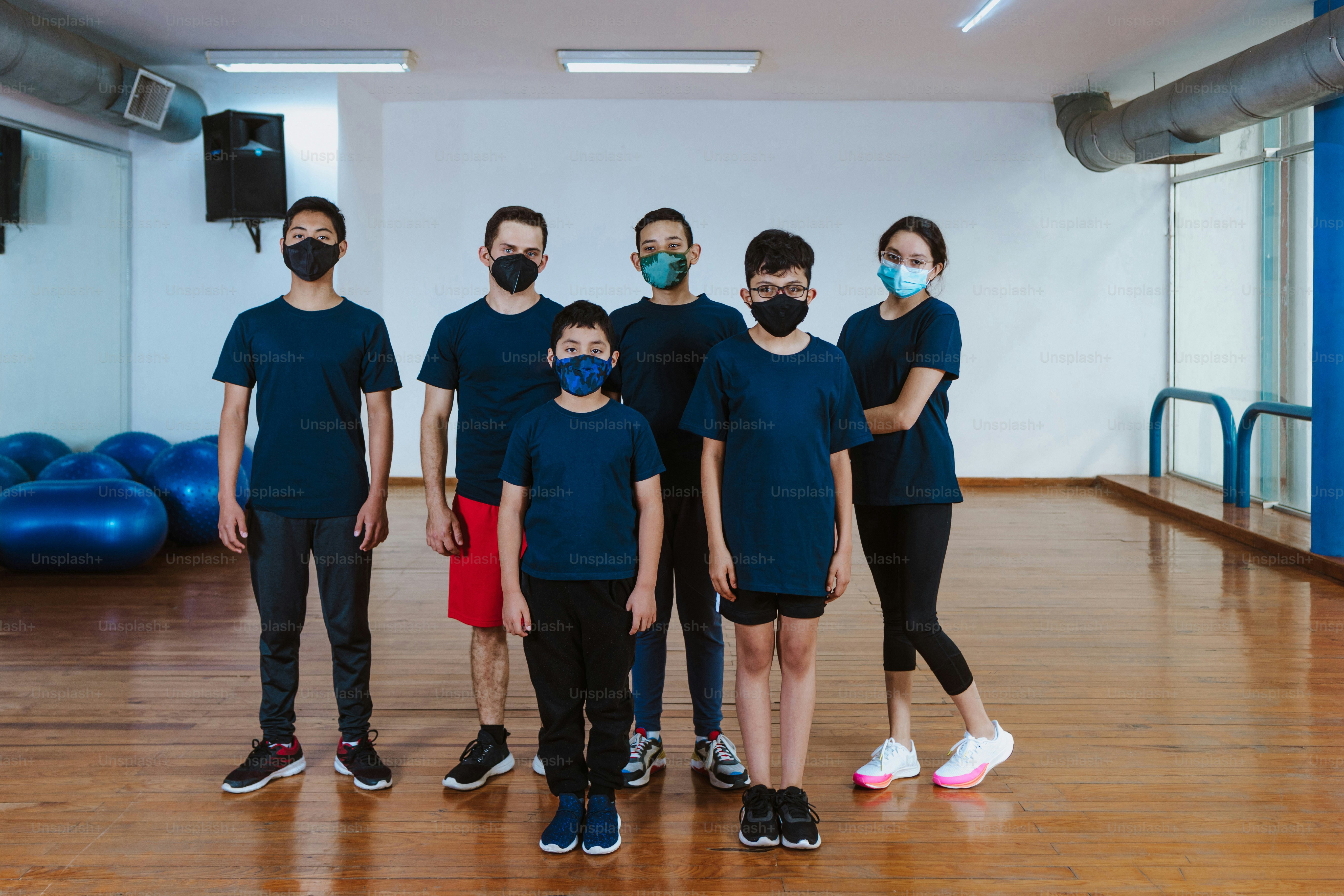 Adolescenti latini e bambini ispanici con l'istruttore uomo con maschera facciale per la pandemia di coronavirus covid in classe di sport di allenamento in Messico America Latina