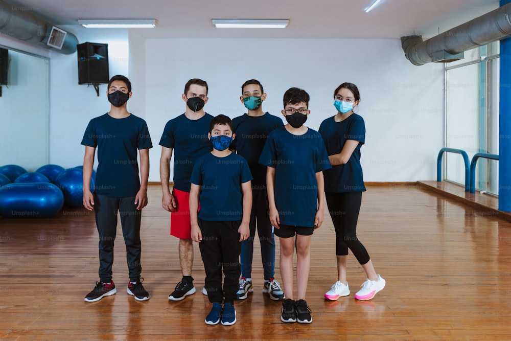 Latin teenagers and hispanic children with instructor man with face mask for coronavirus covid pandemic in work out sport class in Mexico Latin America