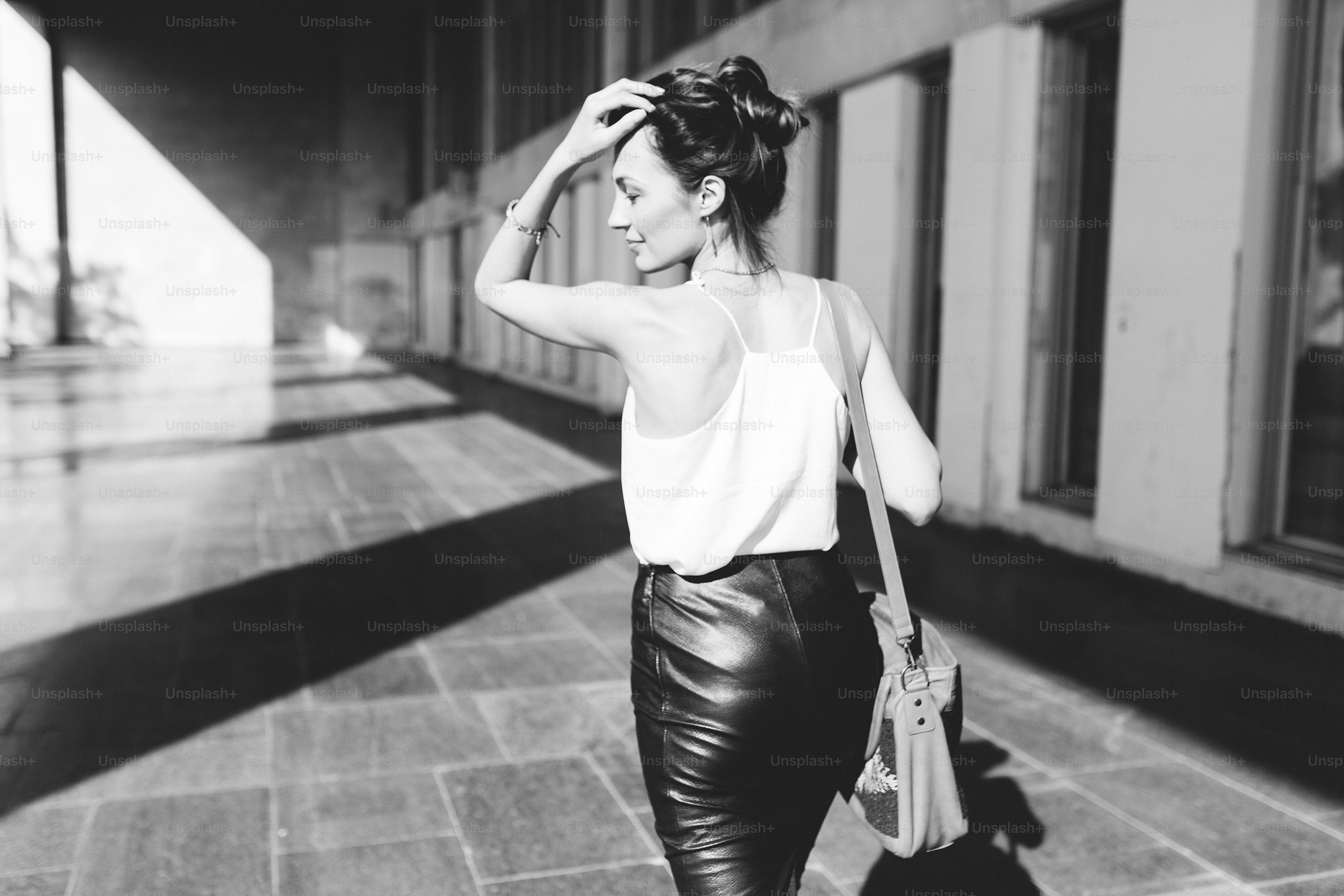 Pretty business woman walking near office building. Black and white photo