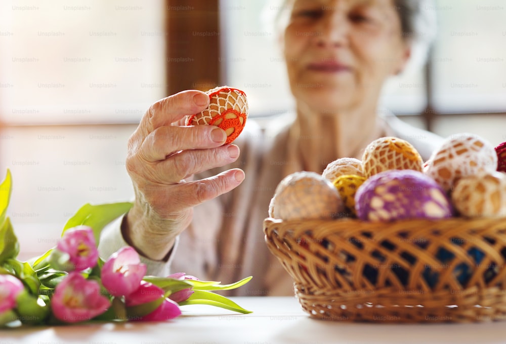 Beautiful senior woman with easter eggs and tulips.