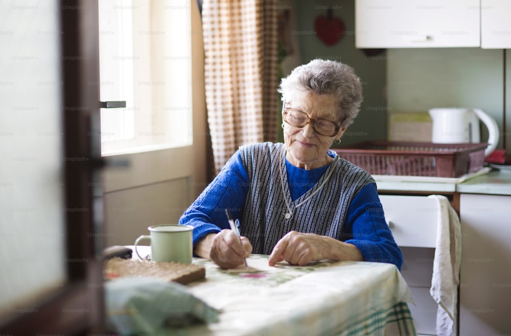 Alte Frau sitzt in ihrer Küche im Landhausstil
