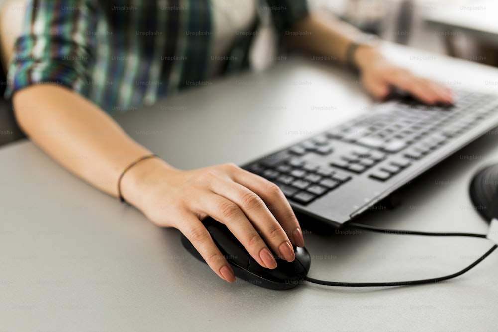 Primo piano di una donna che utilizza una tastiera del computer e un mouse