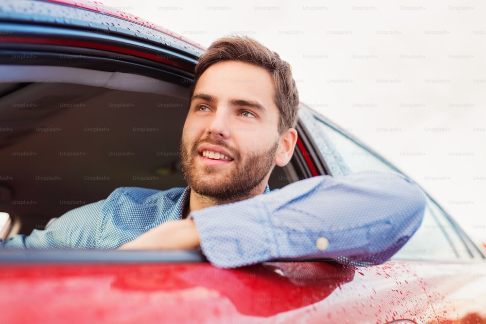 Handsome young man in a blue shirt driving a car