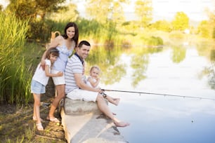 Família feliz jovem com crianças pescando na lagoa no verão