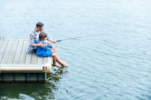 Top view of father and son fishing together on quayside