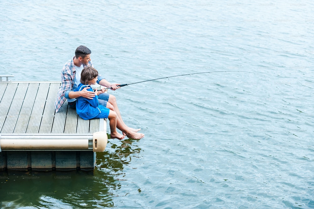 Father holding fishing rod and showing big fish to his son photo