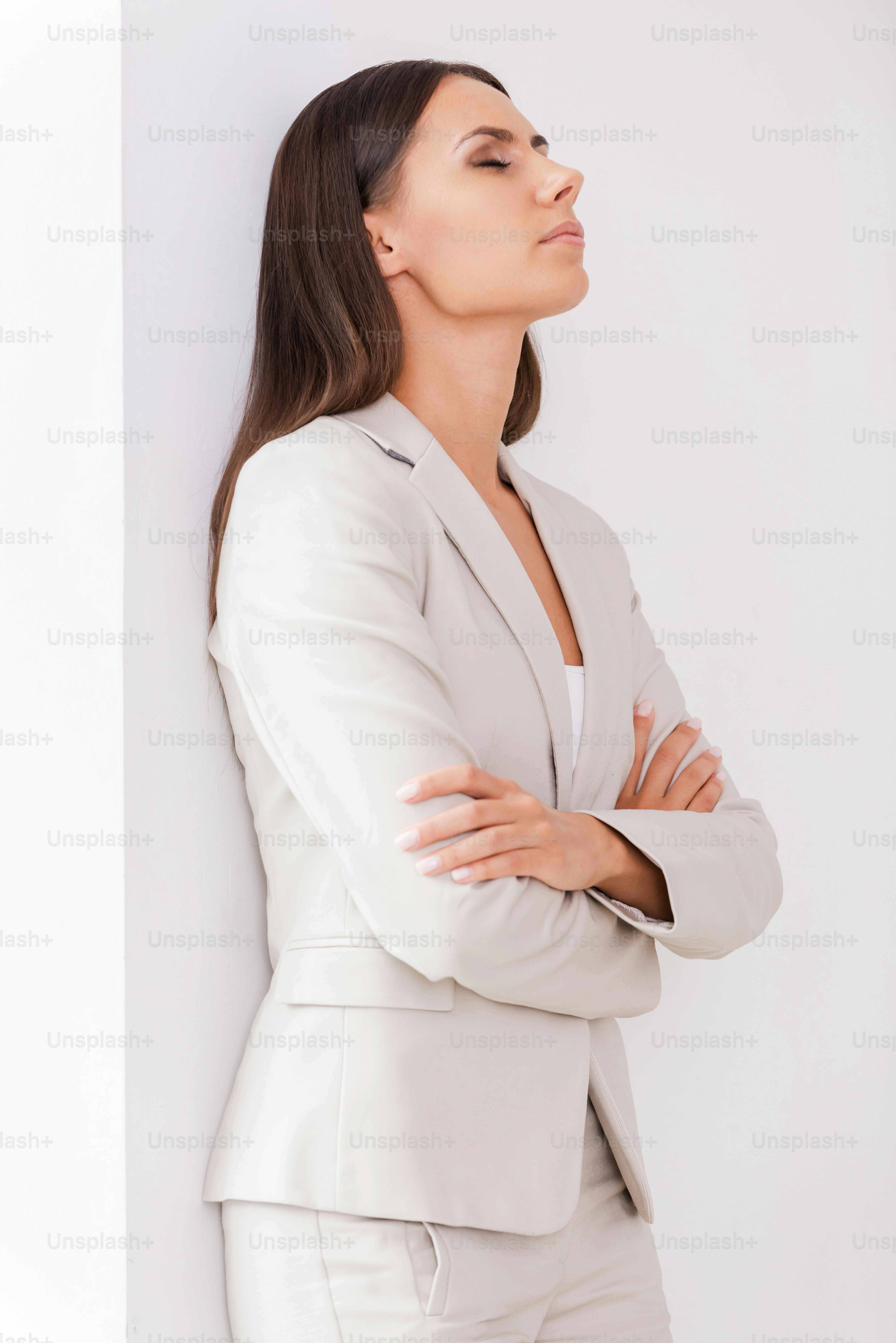 Depressed young businesswoman in suit keeping arms crossed and eyes closed