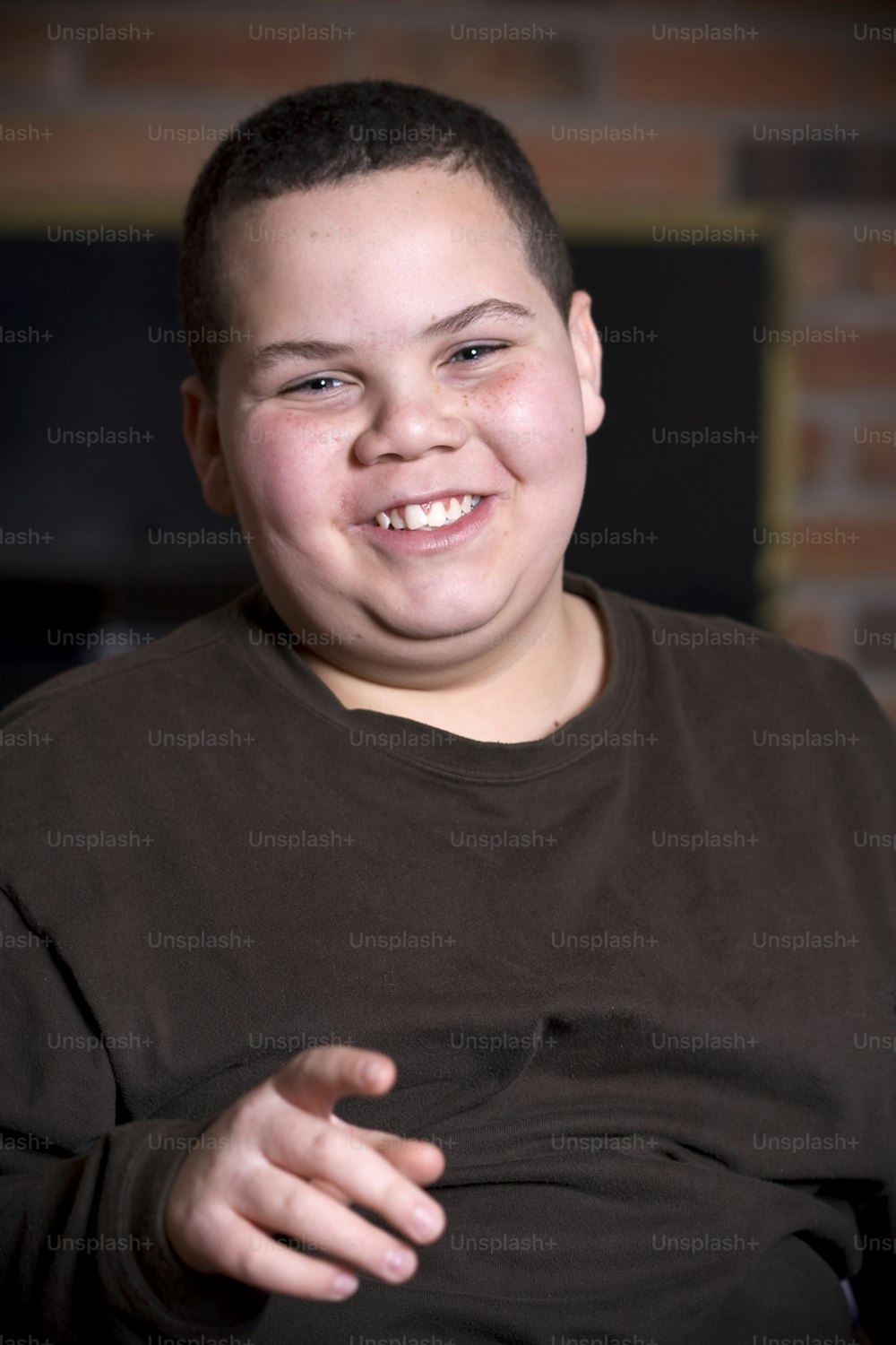 a young boy smiling while sitting in a chair