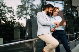 Picture of handsome businessman and attractive businesswoman on break in front of company