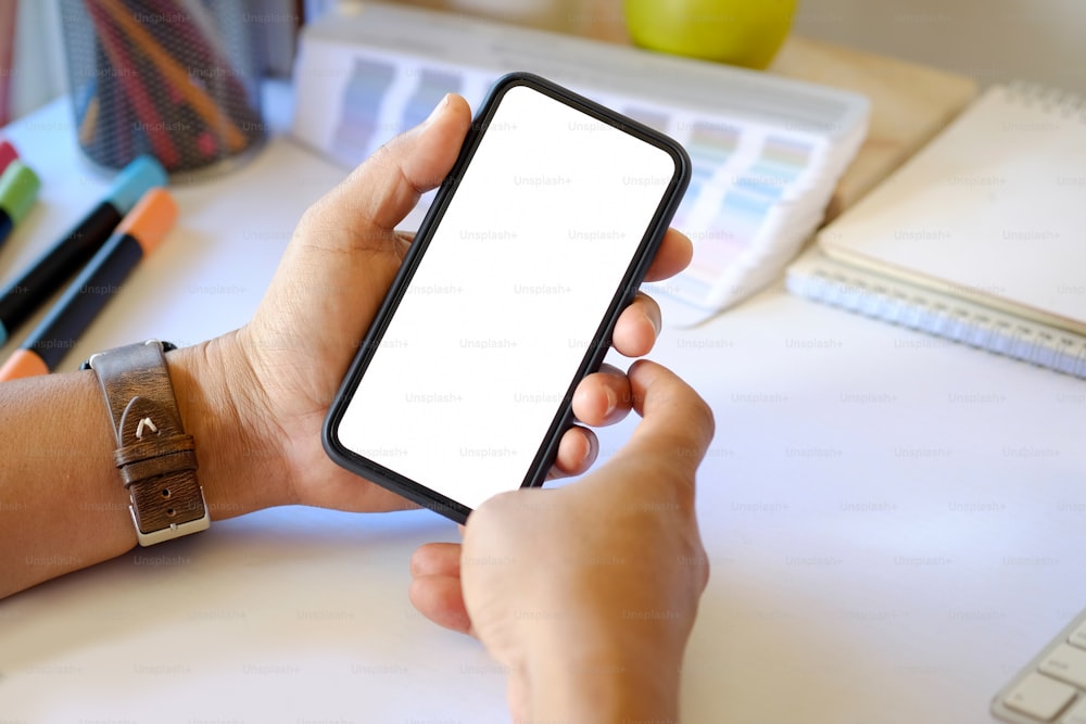 Closes up of an unrecognizable businessman hand holding smartphone on  office desk.