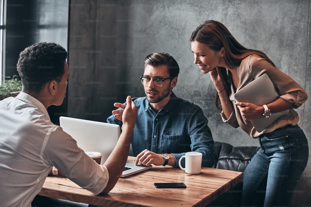 Group of young confident business people discussing something while spending time in the office